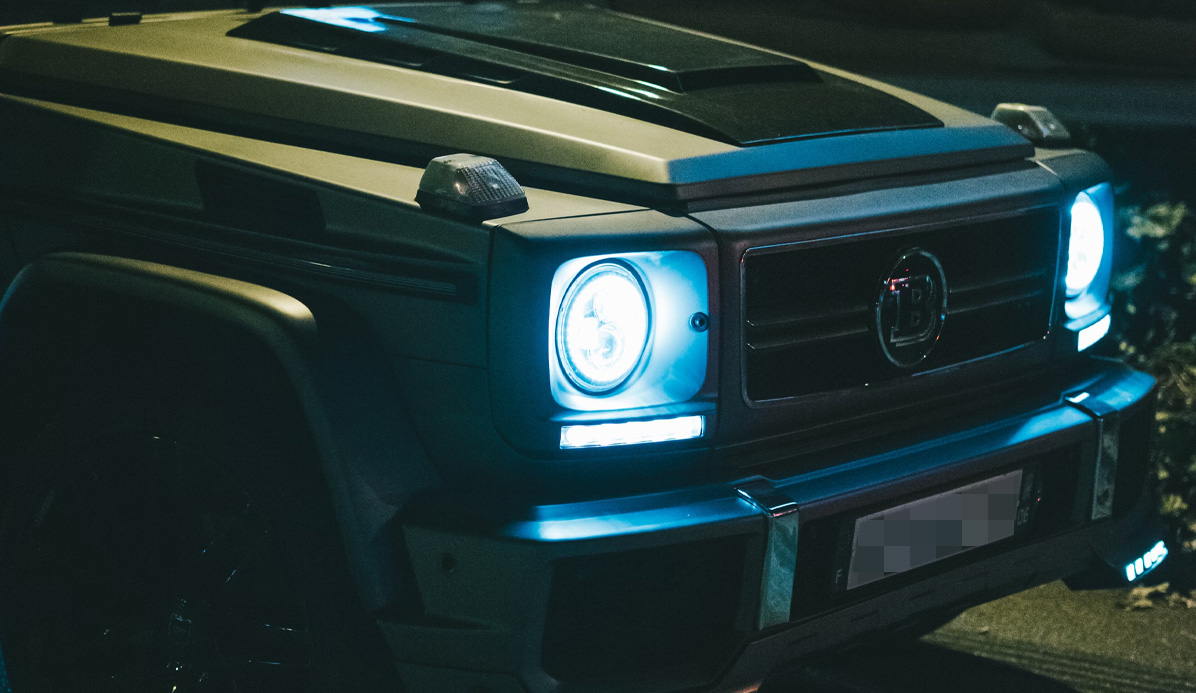 Närbild av framsidan på en bil med tända strålkastare