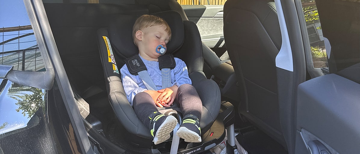 Litet barn somnar i bilbarnstol under bilresa