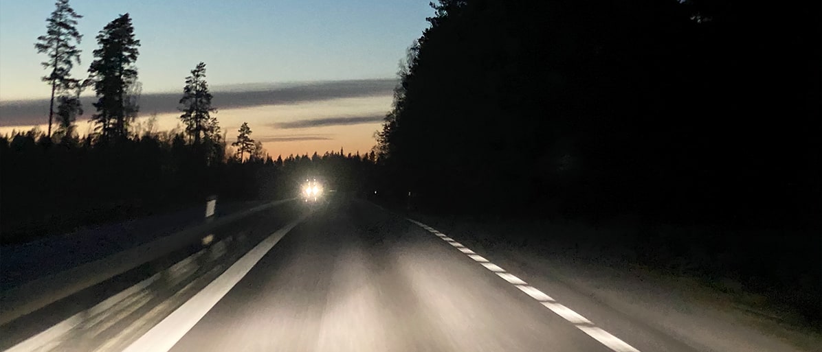 Bilfärd på en landsväg omringad av skog i skymningen