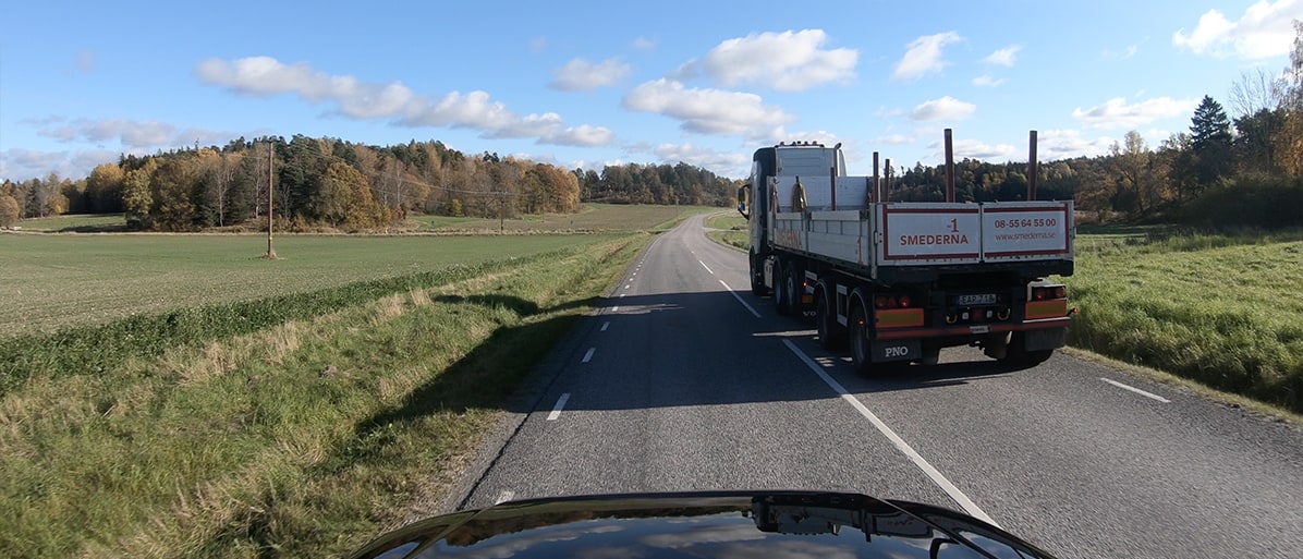Omkörning av lastbil på en landsväg omgiven av öppna fält