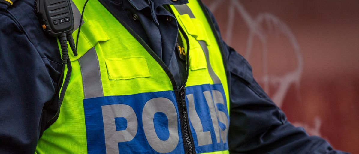 Närbild på en polisuniform med reflekterande väst.