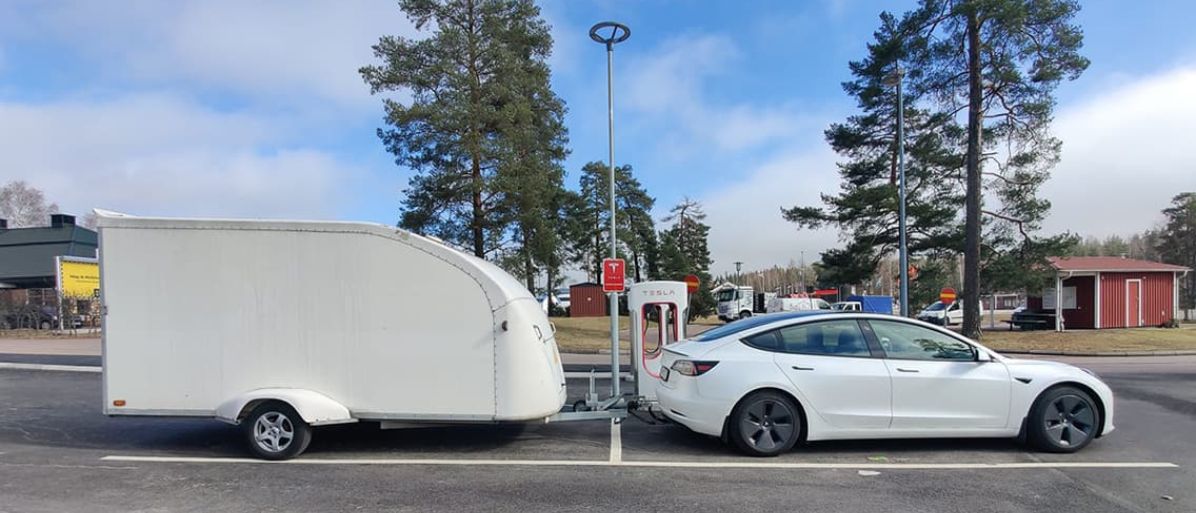 Bil med kopplad släpvagn parkerad vid en laddstation