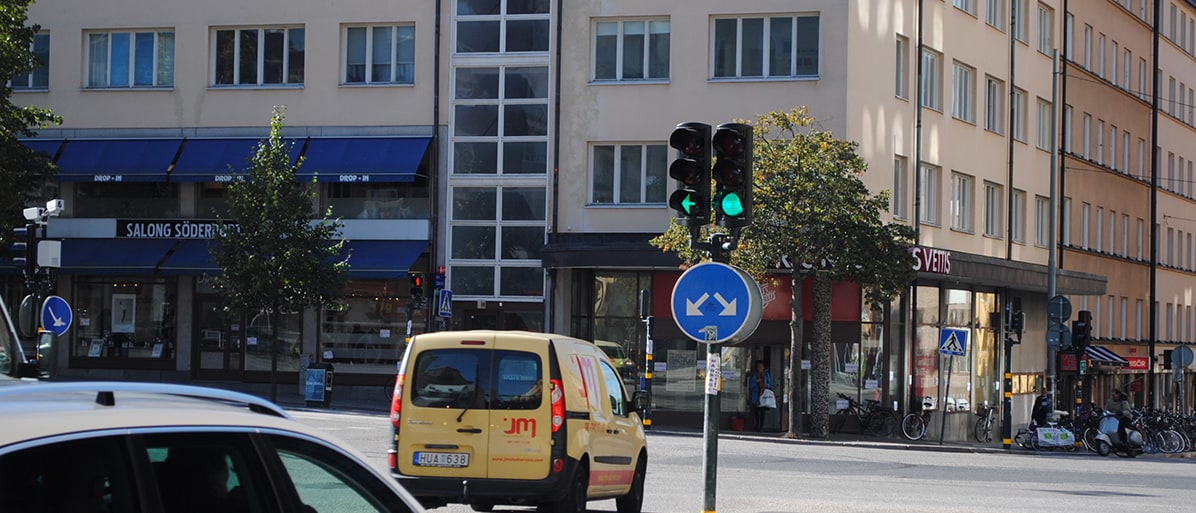 Trafikljus i en stadskorsning visar grönt ljus, med ett påbudsmärke som anger att fordon måste svänga vänster eller höger.