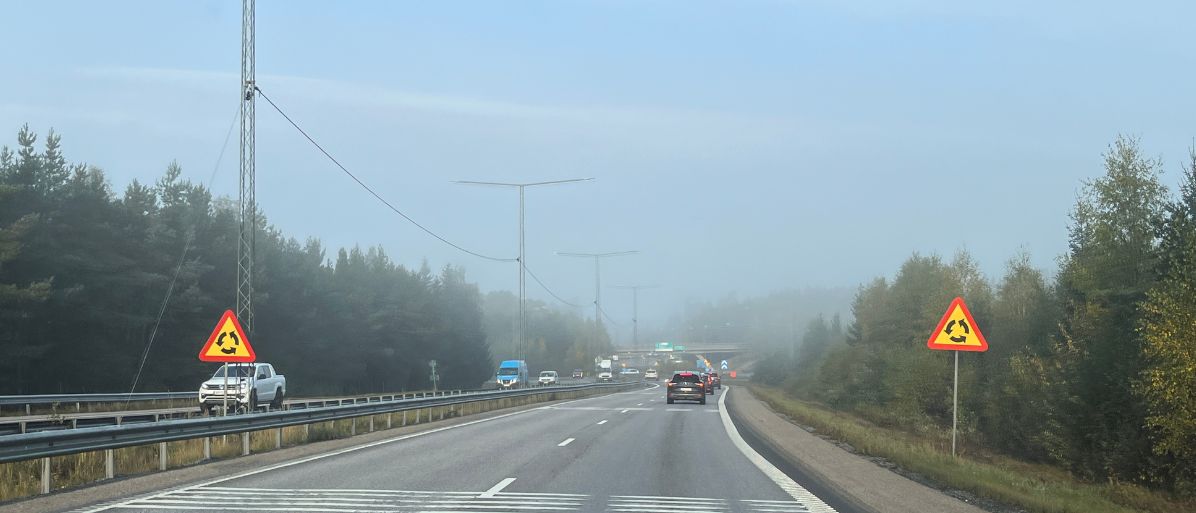 Bilväg i dimma med varningsskyltar