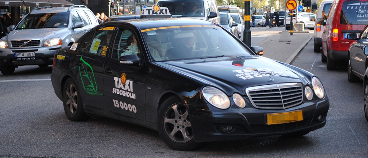 Taxi med takskylt som kör på en gata i staden