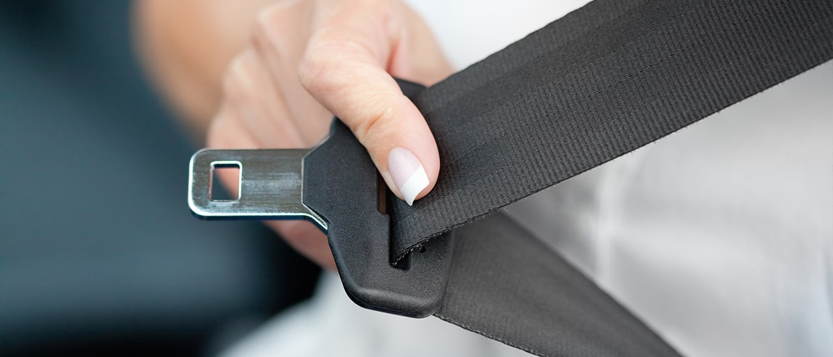 Hand som spänner fast ett trepunktsbälte i en bil