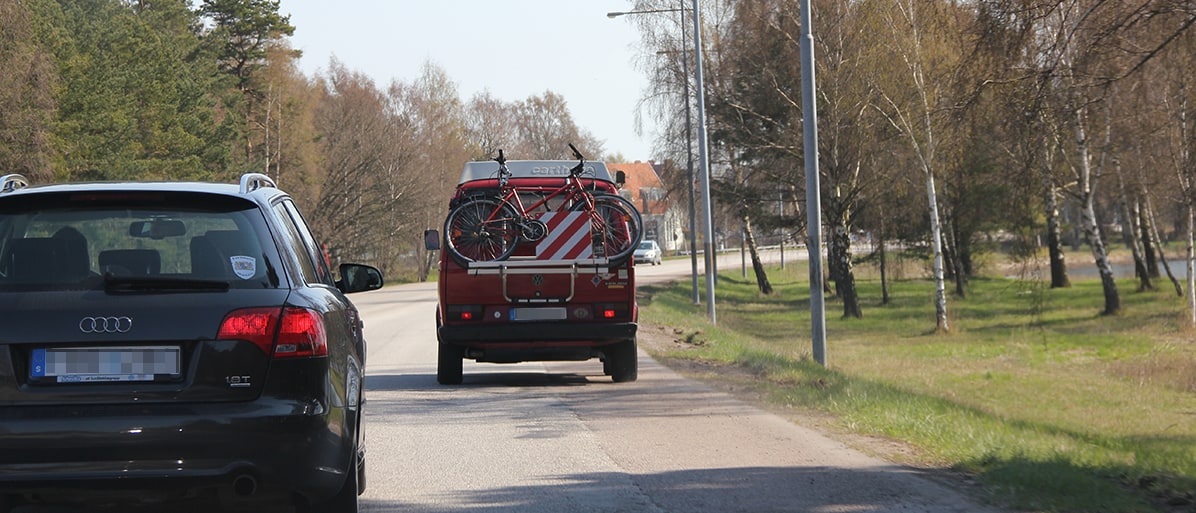Bil med cykelställ på bakdelen, som kör på landsväg