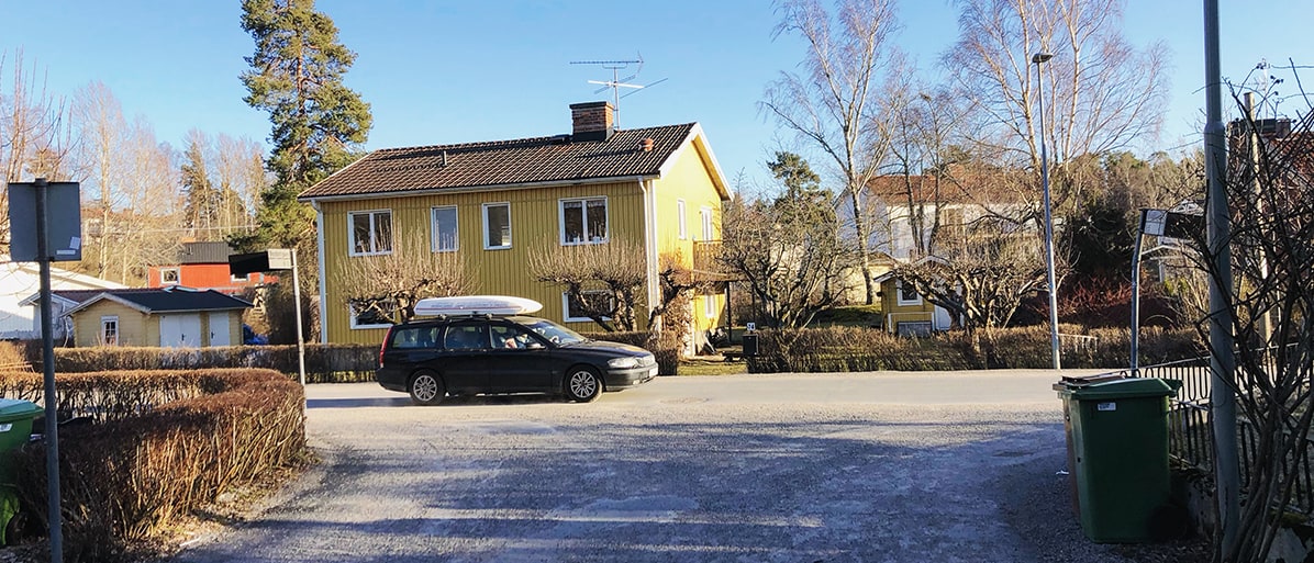 En bil parkerad framför ett hus med gula väggar