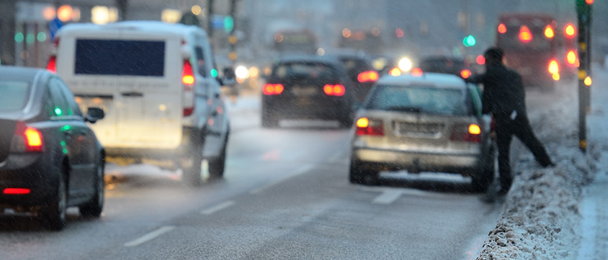 Bilar på en väg med dimmigt väder och varningsblinkers på några av fordonen