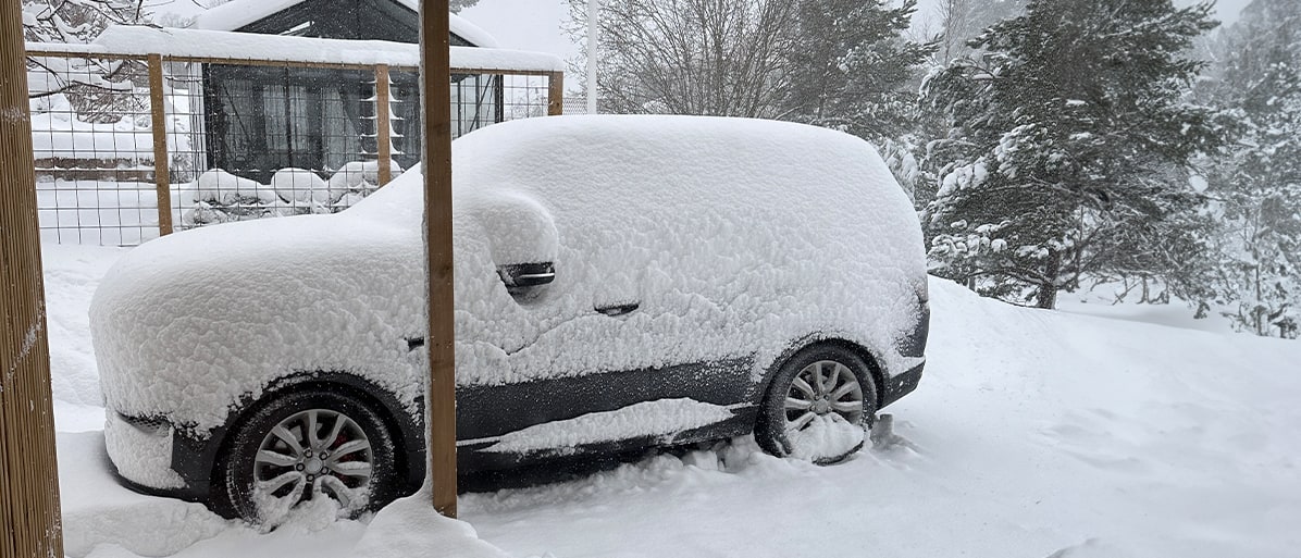 En bil täckt med snö i vinterväde